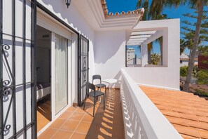 A balcony with a white railing, a small table, and two chairs. - Torremolinos Coliving Playa (Torremolinos)