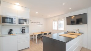 A modern kitchen with built-in microwaves, a coffee maker, and a large island with a cutting board. - Torremolinos Coliving Playa (Torremolinos)