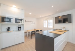 A modern kitchen with built-in microwaves, a coffee maker, and a large island with a cutting board. - Torremolinos Coliving Playa (Torremolinos)