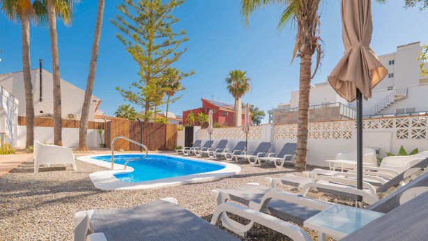A pool area with lounge chairs, a small pool, and palm trees. - Torremolinos Coliving Playa (Torremolinos)
