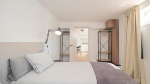 A hotel room with a bed, bedside lamp, wardrobe, and an open door leading to a bathroom. - Torremolinos Coliving Playa (Torremolinos)