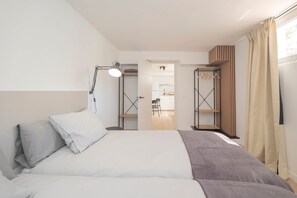 A hotel room with a bed, bedside lamp, wardrobe, and an open door leading to a bathroom. - Torremolinos Coliving Playa (Torremolinos)