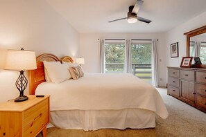 A bedroom with a bed, bedside tables, a ceiling fan, a dresser, and a window with a view of trees. - Cozy Condo Ranch at Roaring Fork (Carbondale)