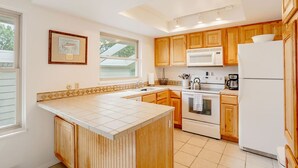 A kitchen with wooden cabinets, a white refrigerator, a stove, and a microwave.