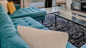 Una sala de estar moderna con un sofá azul, una chimenea, un televisor y un ventilador de techo.