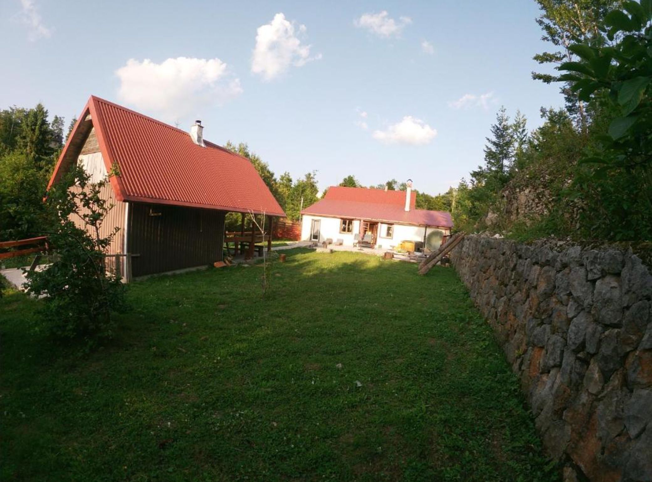 A rural property with a barn, a white house, and a stone wall.