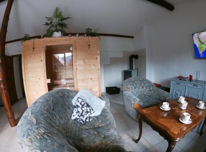 Un salon chaleureux avec une porte en bois, deux canapés à motifs, une table basse en bois et une carte accrochée au mur.