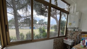 Un bagno con un'ampia finestra, un termosifone, un lavandino e uno scaldabagno.
