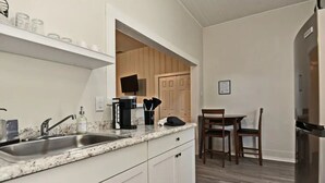 Une cuisine dotée d’un plan de travail en granit, d’un évier en acier inoxydable et d’un coin repas avec une table et des chaises en bois.
