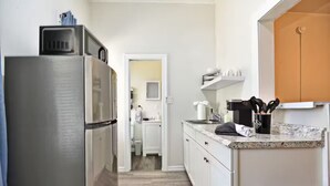Une cuisine équipée d’un réfrigérateur en acier inoxydable, d’un plan de travail avec une machine à café et d’une poubelle.
