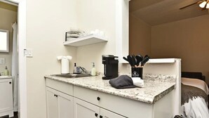Une cuisine compacte dotée d’un plan de travail en granit, d’une machine à café et d’un bloc à couteaux.