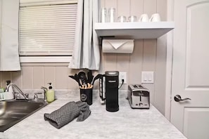 Eine Küche mit Spüle, Wasserkocher, Toaster und einem Handtuch auf der Arbeitsfläche.