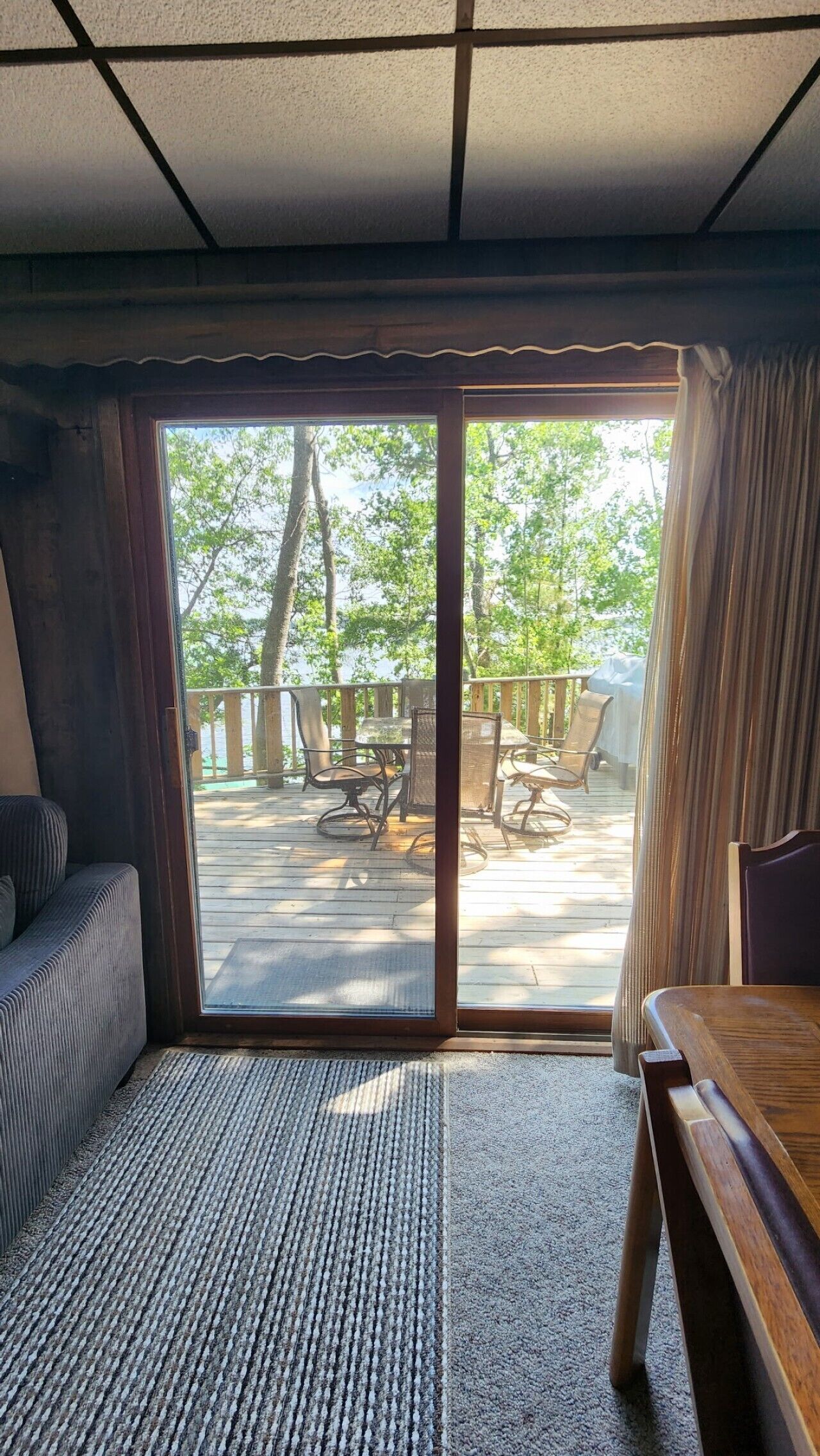 A room with a sliding glass door leading to an outdoor deck with a table and chairs.