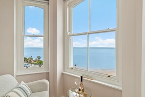 Ein Zimmer mit zwei großen Fenstern und Meer- und Strandblick.