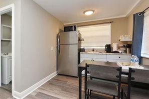 A compact kitchen with a refrigerator, microwave, and a dining area with a table and chairs. - Efficiency Apt #6 Near Downtown & Bike Trail (Winter Garden)