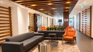 Eine moderne Lobby mit einer Couch, Sesseln, einem Couchtisch und einem gemusterten Boden.
