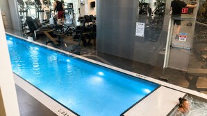 Ein Pool mit Whirlpool, Fitnessgeräten und einer Glaswand.