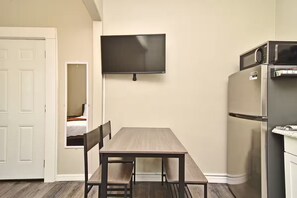 Eine kompakte Küche mit Flachbildfernseher, Kühlschrank und Esstisch mit Stühlen.