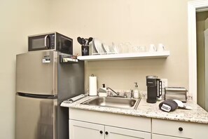 Eine Küche mit Edelstahl-Kühlschrank, Mikrowelle, Spüle und Kaffeemaschine.