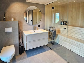 A modern bathroom with a white sink, a mirror, a toilet, and a glass shower enclosure.