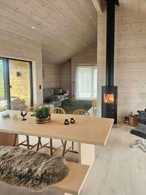 A cozy cabin interior with a wooden interior, a fireplace, a dining area, and a sofa.