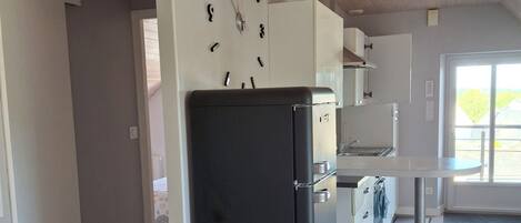 A modern kitchen with a black refrigerator, white cabinets, and a wall clock.