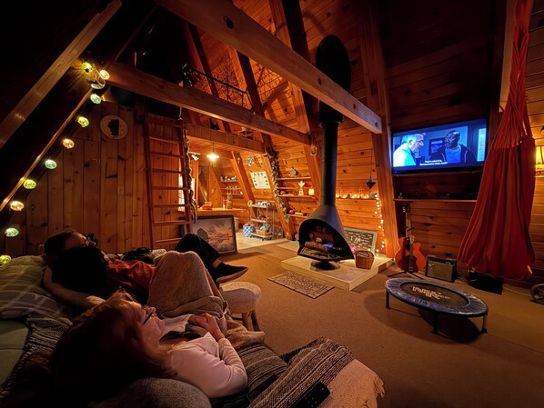 A cozy log cabin interior with a fireplace, wooden walls, a television, and a trampoline.