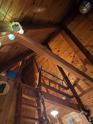 A wooden interior with a sloped ceiling, a spiral staircase, and a disco ball.