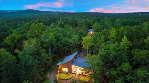 Ein abgelegenes Blockhaus, umgeben von dichtem Wald, mit sichtbarer Terrasse und Außenbeleuchtung.