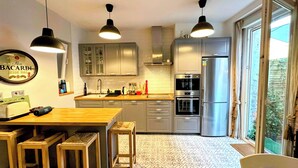 A modern kitchen with a dining area, stainless steel appliances, and a large window. - Pepe house (Areeta / Las Arenas)