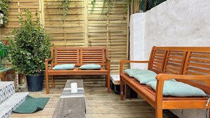 A wooden bench and sofa set with cushions, a potted plant, and a mat on a wooden deck. - Pepe house (Areeta / Las Arenas)