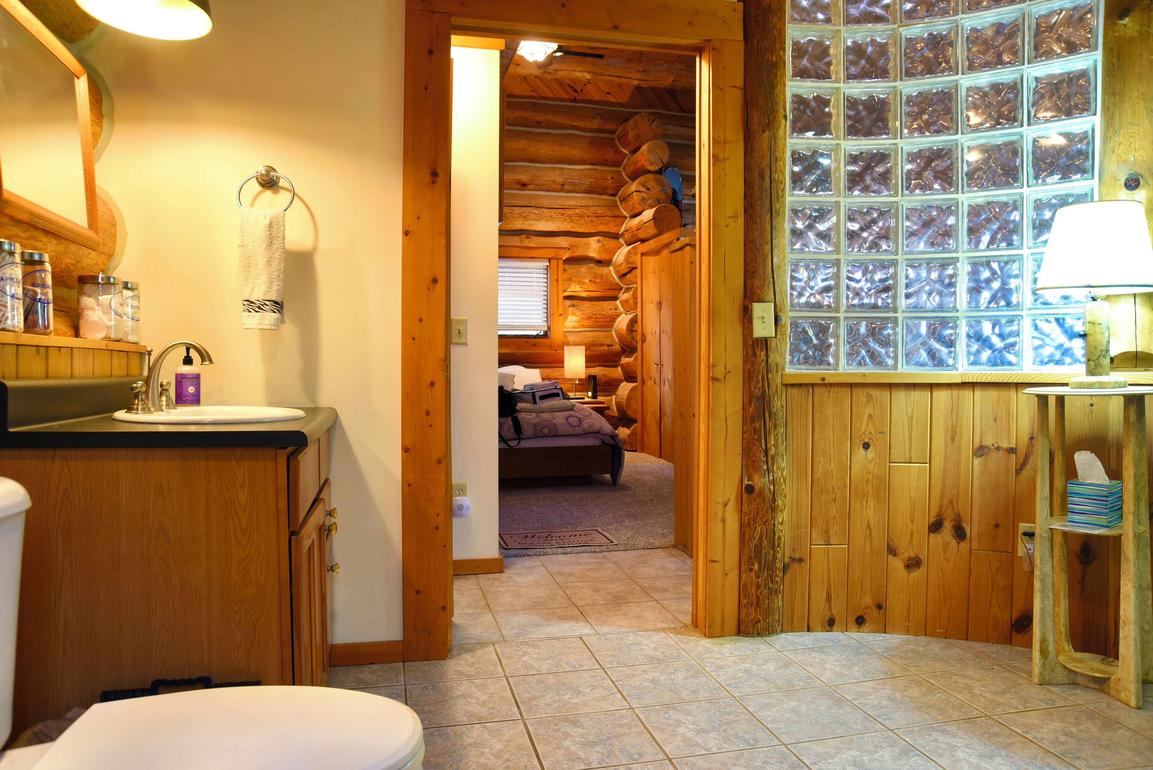L’intérieur d’un chalet en bois comprend une salle de bain, une chambre avec un lit et une fenêtre donnant sur un paysage agréable.