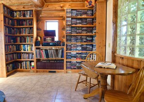 A wooden interior with bookshelves, a table, and a chair. - Log cabin in the woods with views of Lake MI, Located in historic Cross Village (Harbor Springs)