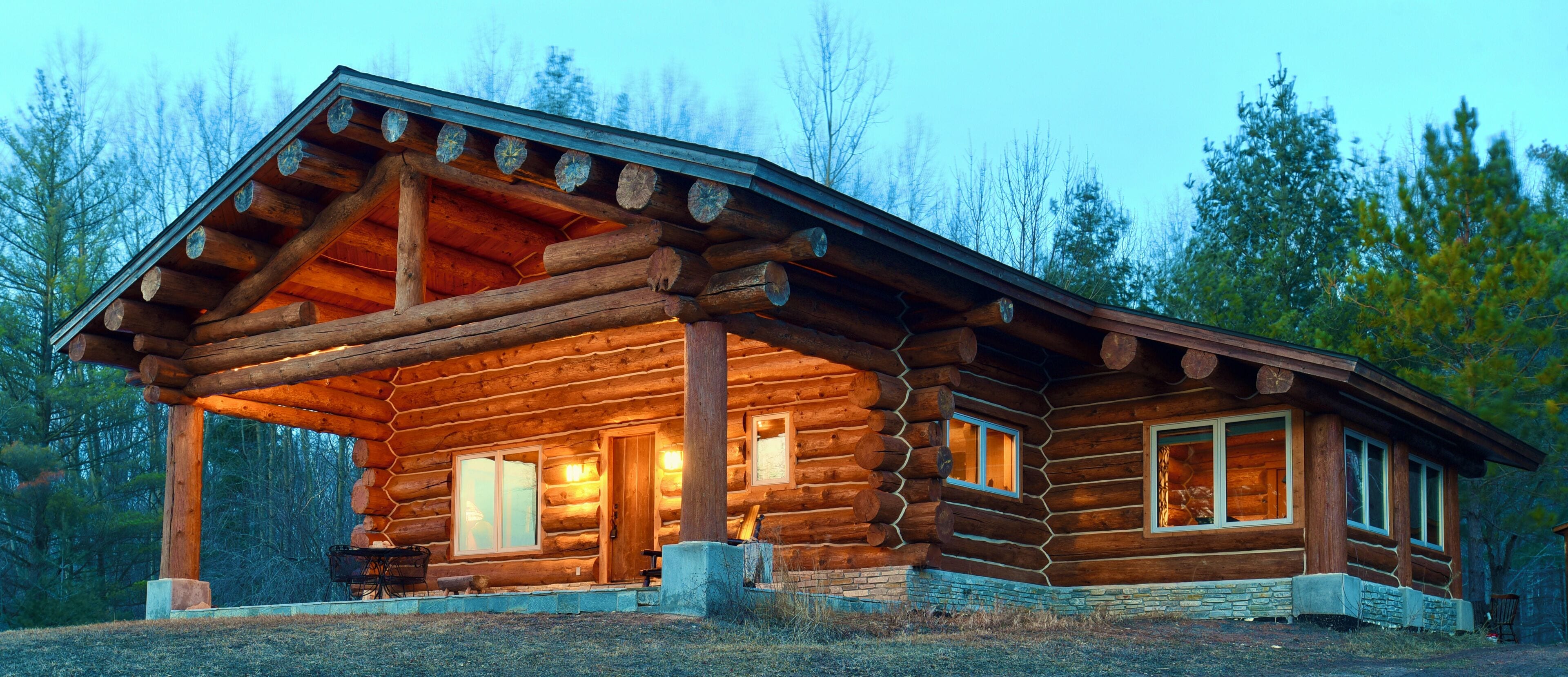 Eine Blockhütte mit Veranda, großen Fenstern und einem Steinfundament.