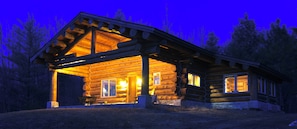 A log cabin with a porch and a chimney, surrounded by trees. - Log cabin in the woods with views of Lake MI, Located in historic Cross Village (Harbor Springs)