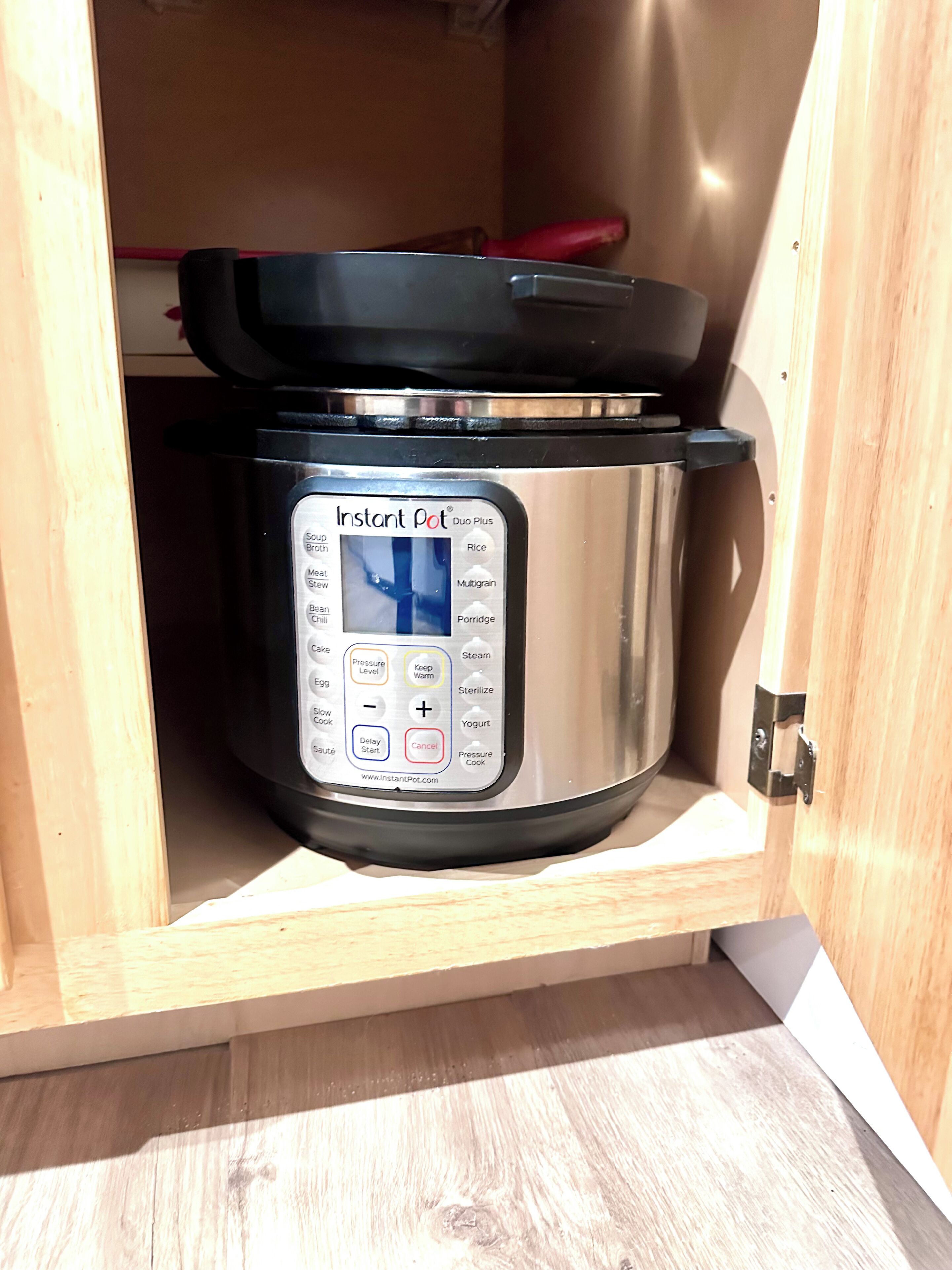 Una olla a presión Instant Pot Duo Plus dentro de un armario de madera.