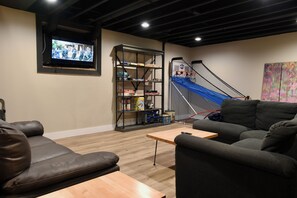 Ein Wohnzimmer mit Fernseher, einer Couch, einem Couchtisch, einem Bücherregal und einer Treppe.