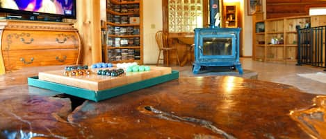 A wooden interior with a television, shelves with items, a blue fireplace, and a wooden table.