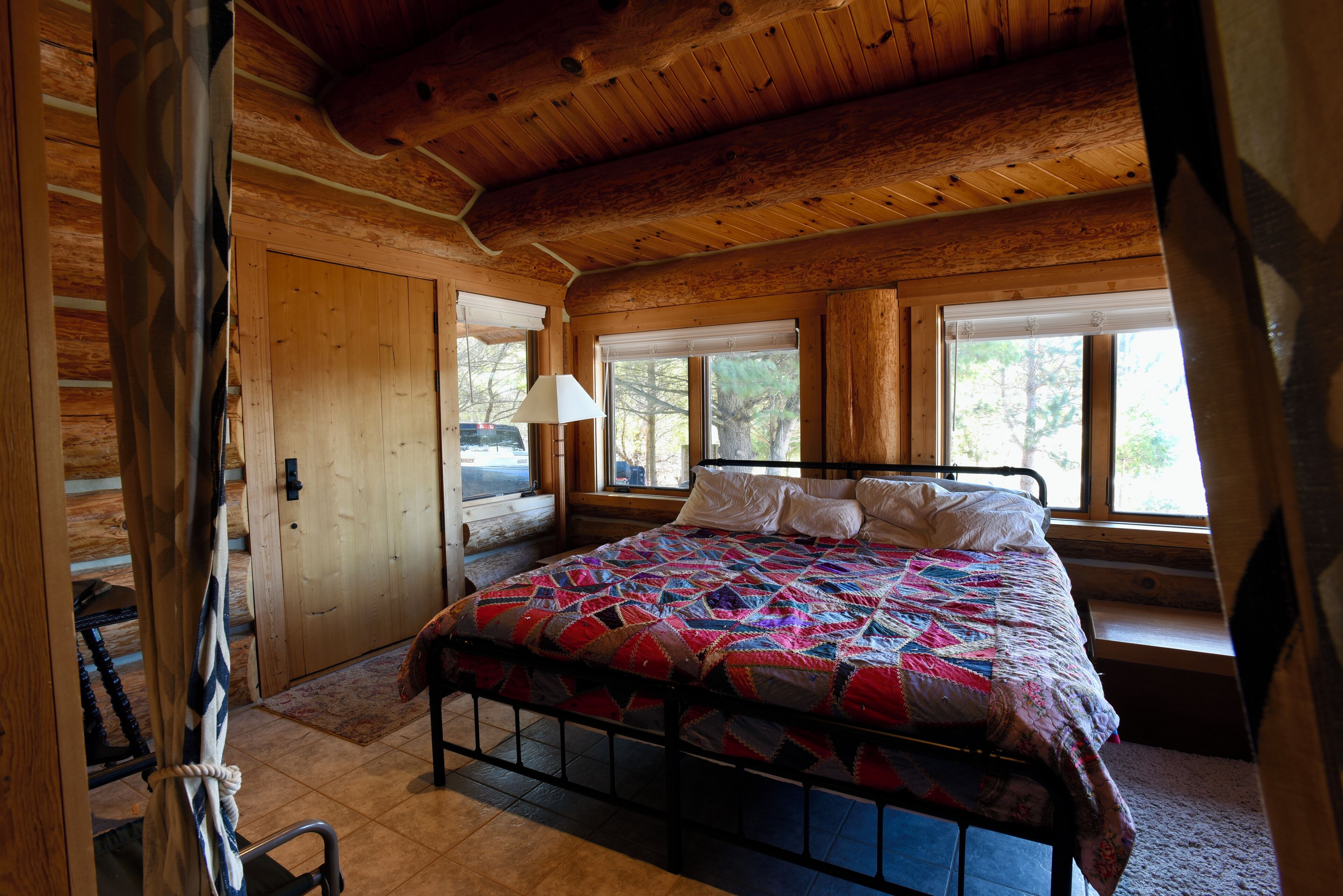 Een houten slaapkamer met een bed, een raam en een deur.
