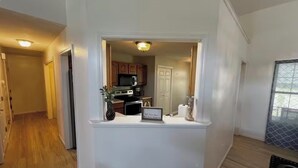 Een moderne keuken met witte kasten, een magnetron en een klein eilandje met een bordje.