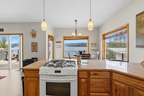 A modern kitchen with a large island, a gas stove, and a view of the outdoors.