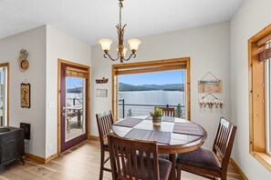 A dining area with a view of a lake, a chandelier, and a wooden table with chairs.