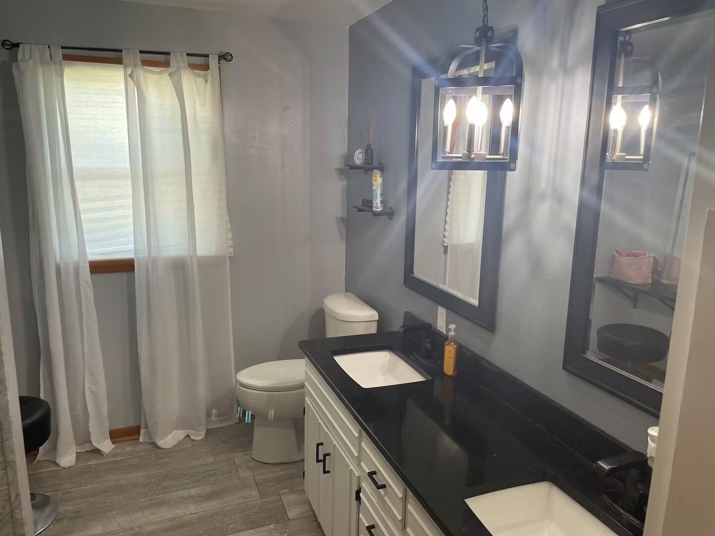 A bathroom with a toilet, a sink, a mirror, and a shower curtain.