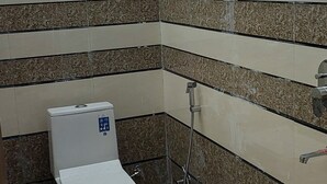 Une salle de bain avec des toilettes, une douche et des murs carrelés.
