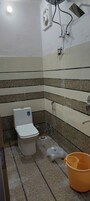 A bathroom with a toilet, shower, and tiled walls.