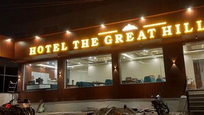 L’extérieur d’un hôtel, avec une enseigne bien visible indiquant : « HÔTEL THE GREAT HILL VIBE ».