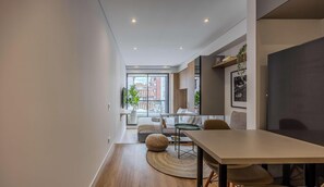 A modern interior with a dining area, a sofa, and a view of the cityscape. - NOK Modern 1BR near Usaquen & Unicentro (Bogota)