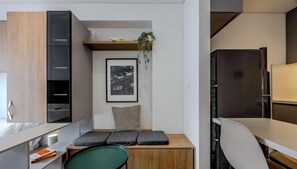 A compact kitchenette with a refrigerator, a small dining area with a chair and a table, and a shelf with a plant. - NOK Modern 1BR near Usaquen & Unicentro (Bogota)