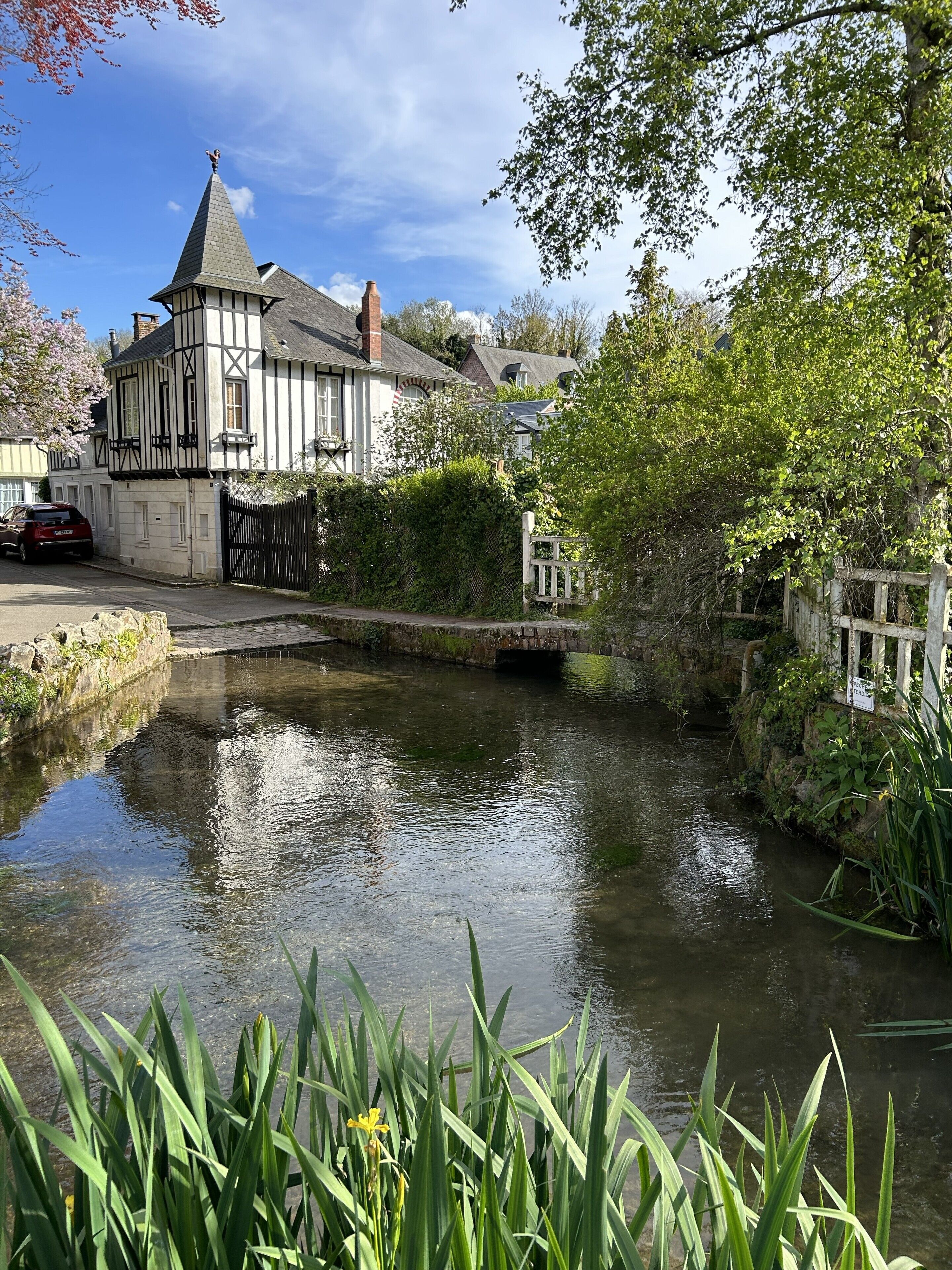 Un bâtiment traditionnel doté d’une tour imposante, bordé d’un étroit canal et entouré d’une végétation luxuriante.