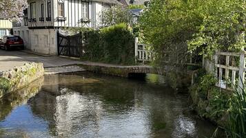 Un bâtiment traditionnel doté d’une tour imposante, bordé d’un étroit canal et entouré d’une végétation luxuriante.